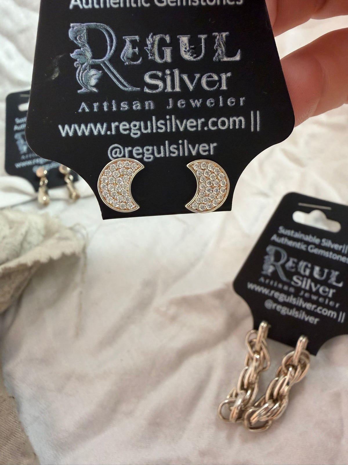 Pair of pave cubic zirconia crescent moon studs on Regul Silver card