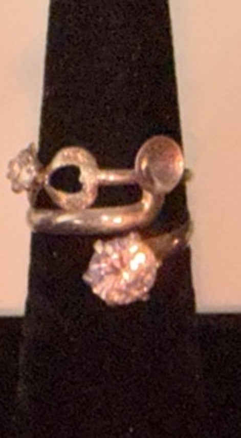 Sterling silver intertwined double-band ring with a cubic zirconia flower cluster on a black display cone, size 7