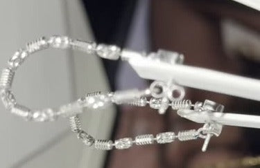 Barrel link hoop earrings in sterling silver with rhodium plate, held on white clips in the DESMOS case at the studio