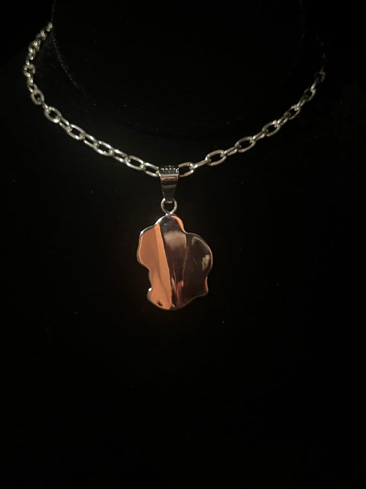 Cowboy hat necklace — back view showing the smooth polished back of the pendant and its sterling chain on black