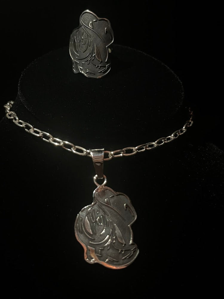 Cowboy hat ring — the ring on a black stand above its matching pendant on a chain, both sterling silver