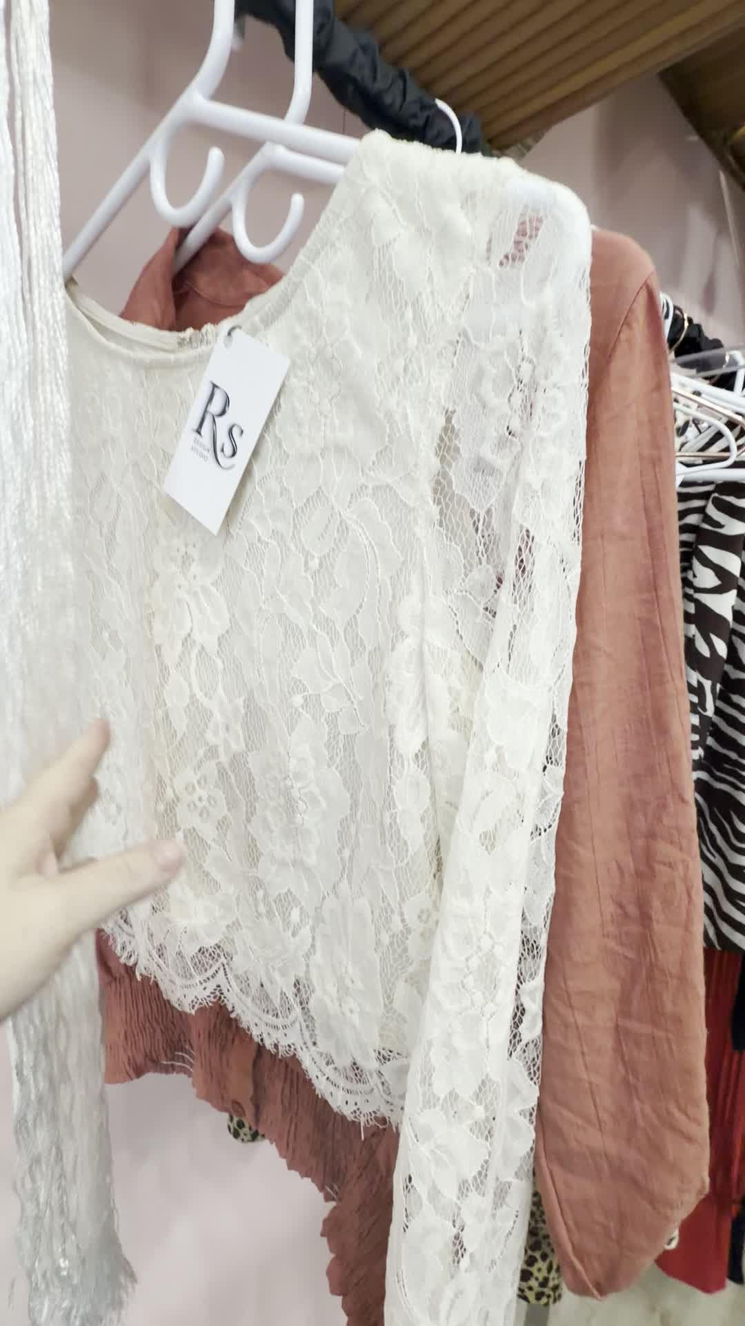 Front view of a like-new white floral lace long-sleeve top on a boutique rack.