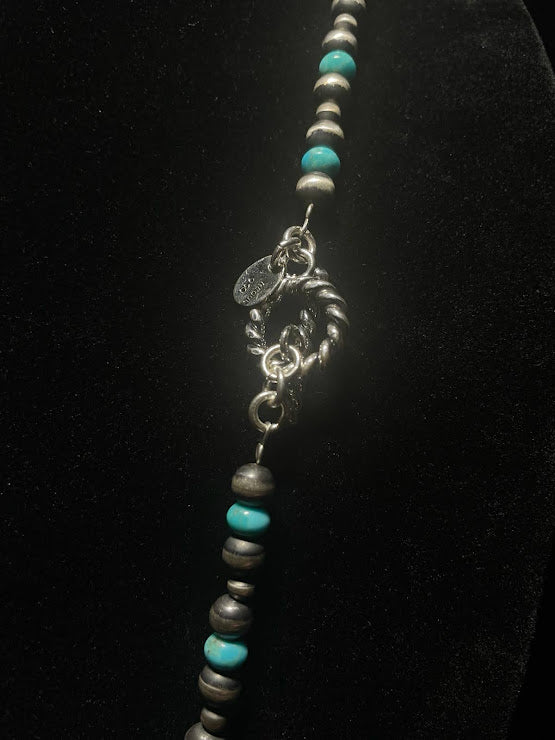 Navajo pearl necklace with turquoise — twisted rope toggle clasp and stamped tag, detail view on black