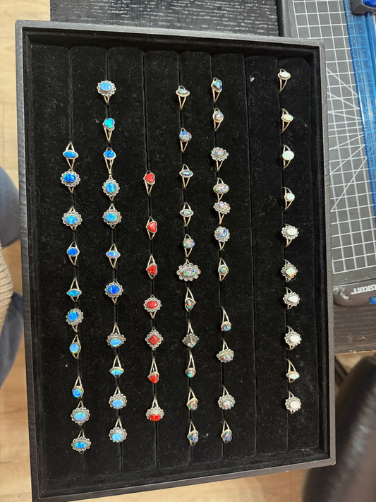 Opalite ring — a black tray of sterling silver opalite rings in light blue, red, kaleidoscope and white