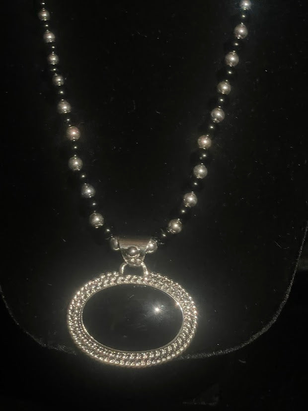 Oval obsidian pendant — full front view of the necklace on its sterling and obsidian pearl strand on black