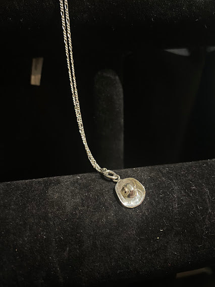 Sterling silver cowboy hat pendant — the silver hat hanging on its chain over a black velvet stand, in full