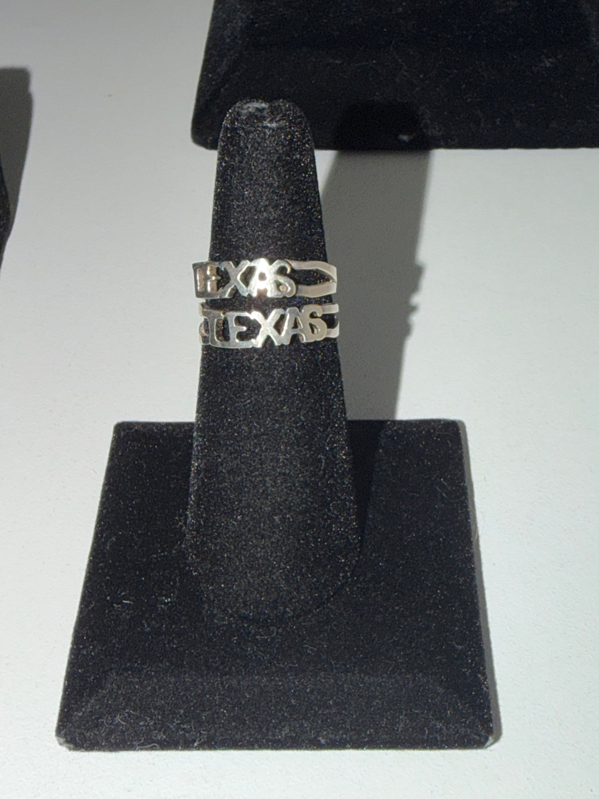 Sterling silver Texas script rings, small and large, on the stand in the Regul Silver case