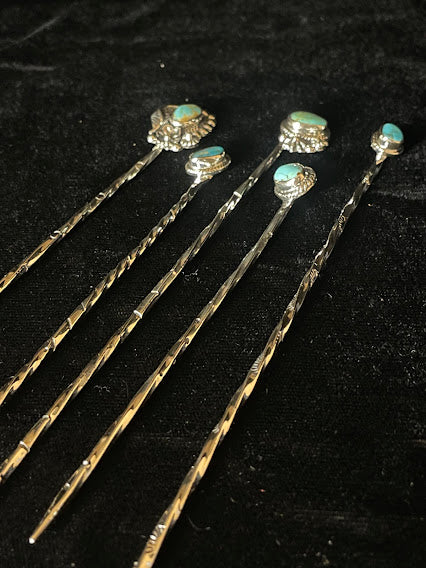 Turquoise hat pin — the back of the pin on a black pillow, its sterling plate, twisted shaft, and clutch