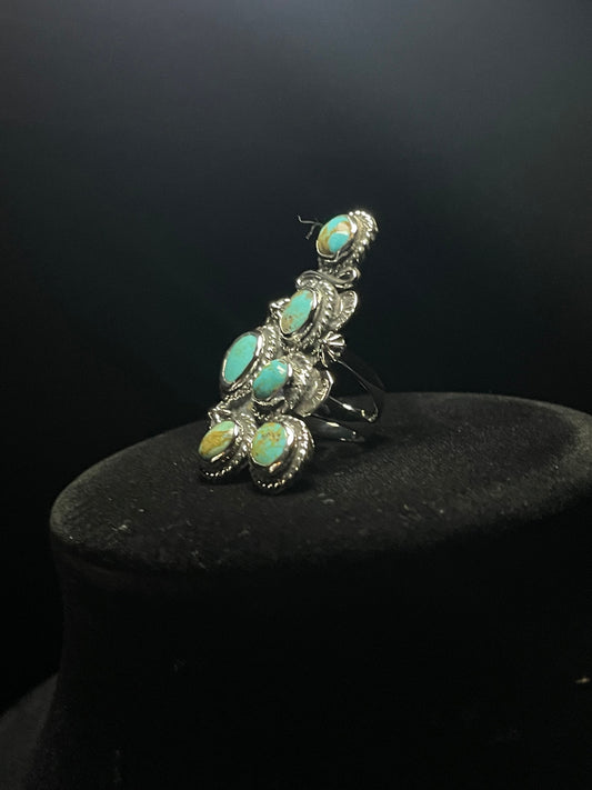 Turquoise ring — six-stone cluster from the side, split shank band and rope bezels showing, on a black stand