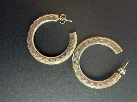 Large thick hammered sterling silver hoop earrings on black background