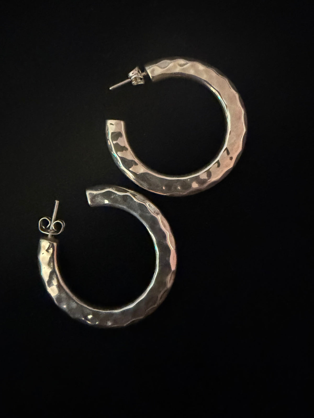 Large thick hammered sterling silver hoop earrings, pair on black
