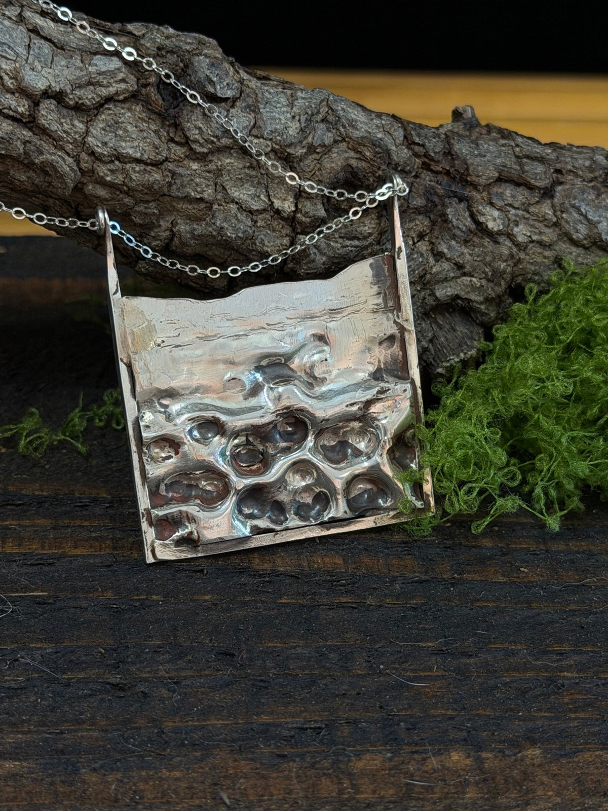 DM30 hammered sterling silver pendant necklace styled on a branch with moss