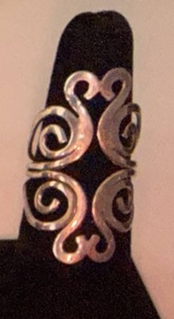 Tall sterling silver four-scroll filigree ring with mirrored openwork curls on a black display cone, size 7