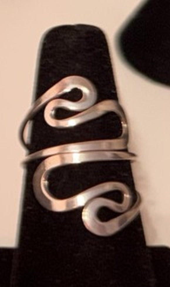 Sterling silver flat S-wave ribbon wrap ring with sweeping curves on a black display cone, size 8