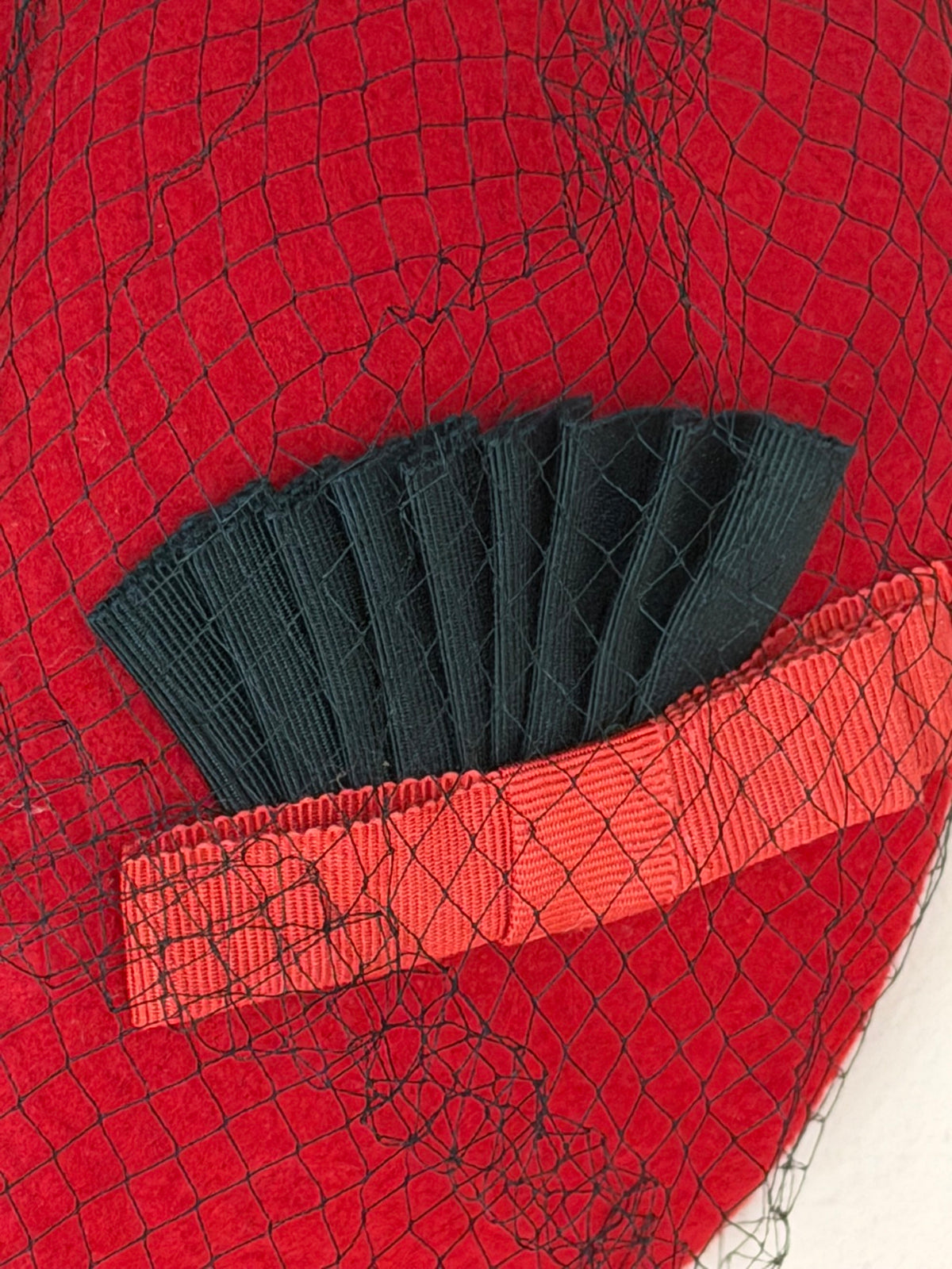 Close-up of the pleated fan and ribbon under the veil on Miss Crosby's vintage red hat