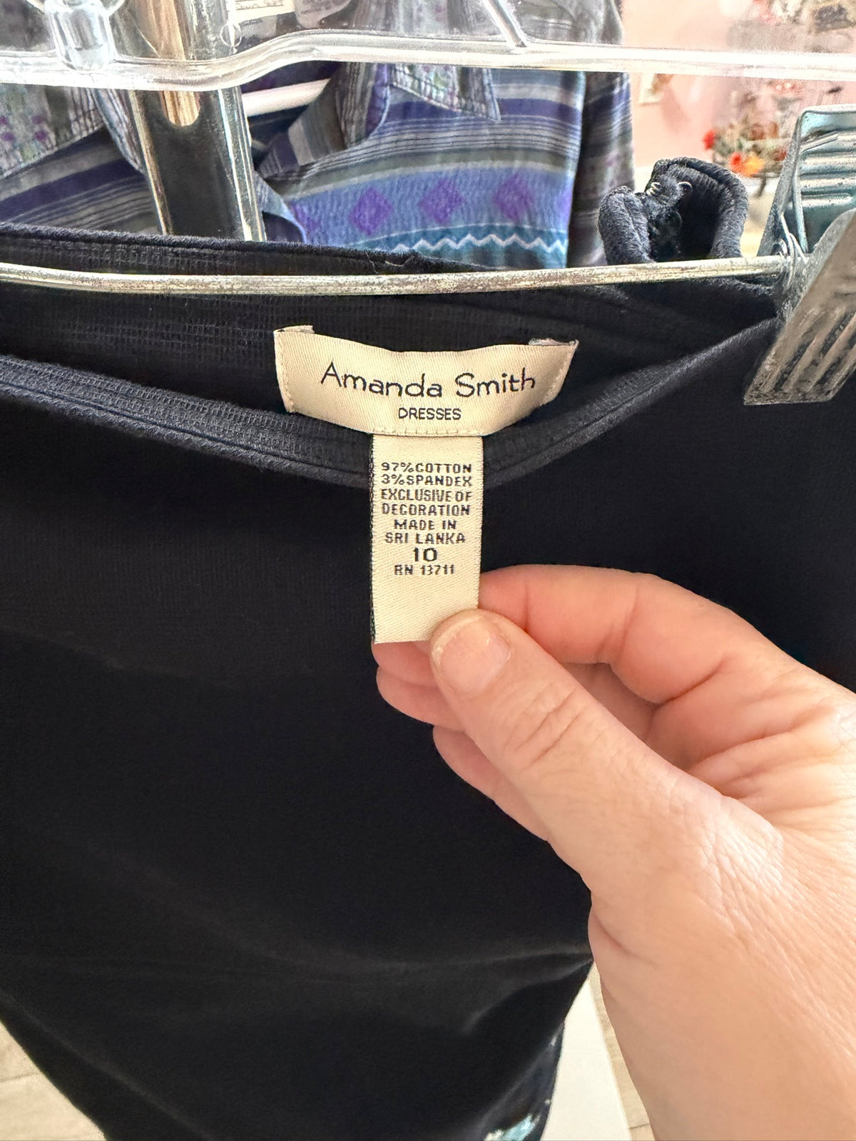 Close-up of the interior clothing tag on a black dress reading Amanda Smith Dresses, 97 percent cotton, size 10.