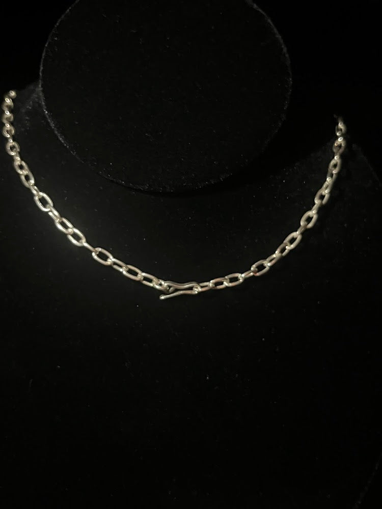 Cowboy hat necklace — detail view of its sterling chain and hook clasp laid on black velvet