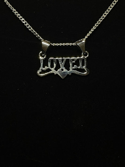 Custom sterling silver word necklace — Loved word pendant with a small heart, front view on a curb chain, on black