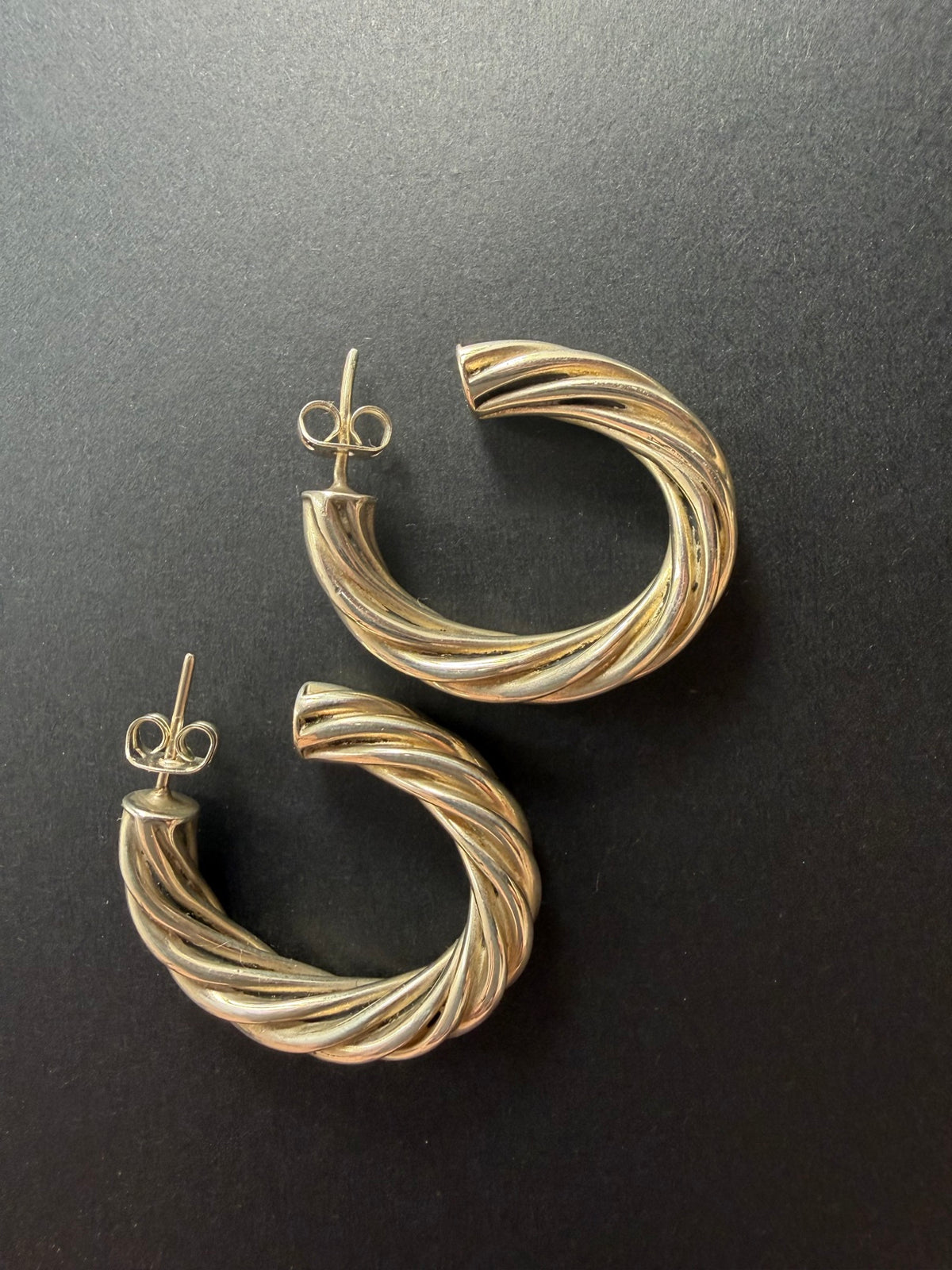 Twisted rope sterling silver hoop earrings close-up on black