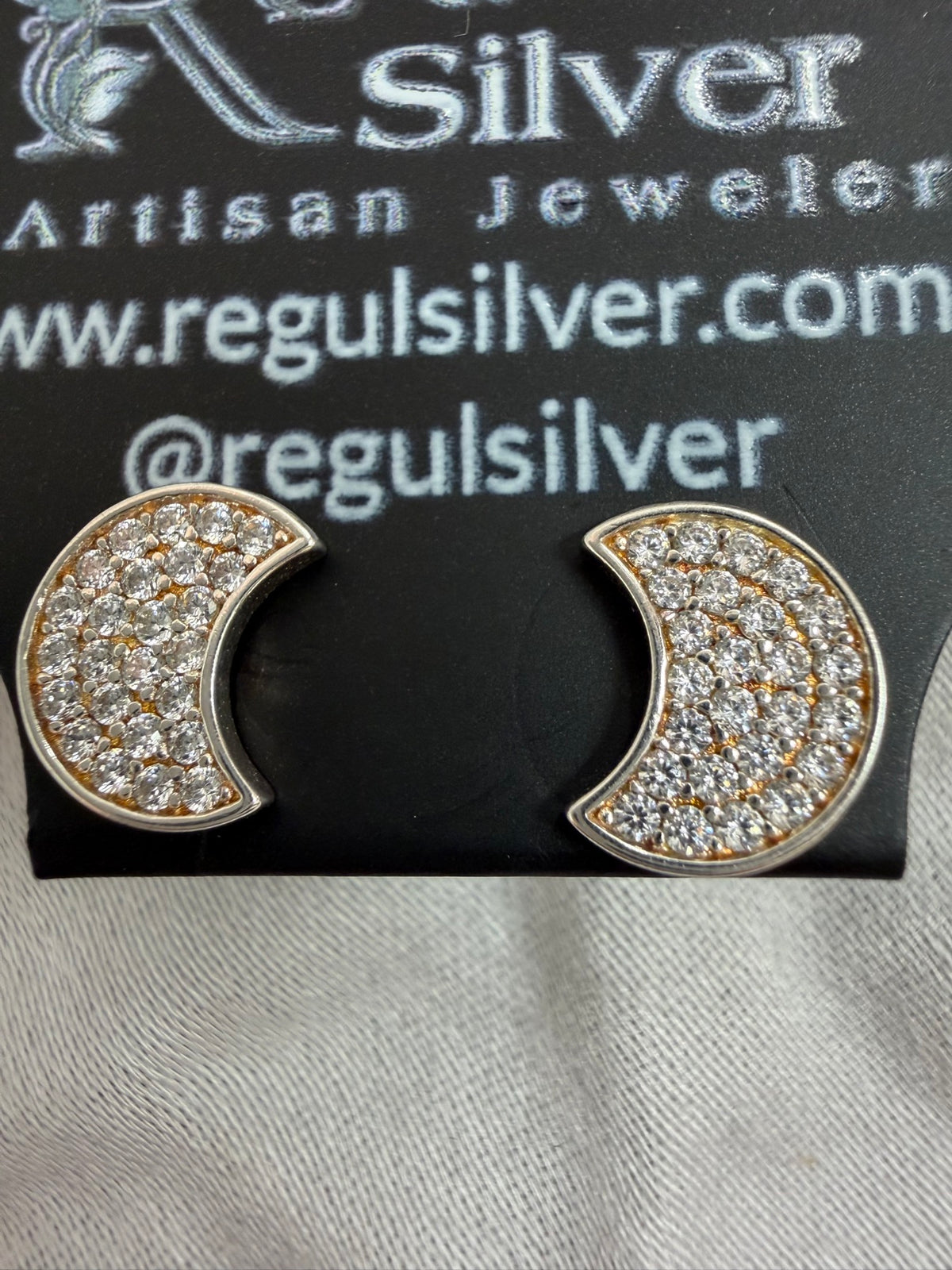 Crescent moon cubic zirconia stud earrings in sterling silver on a Regul Silver display card