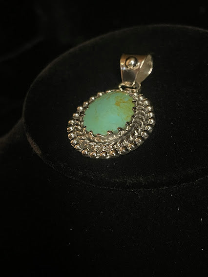 Genuine turquoise pendant - angled front view of the oval stone and its wide silver bail, stone face forward
