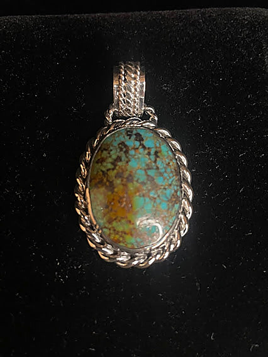 Genuine turquoise pendant - front view of the blue-green oval stone with brown gold matrix in its rope sterling silver frame