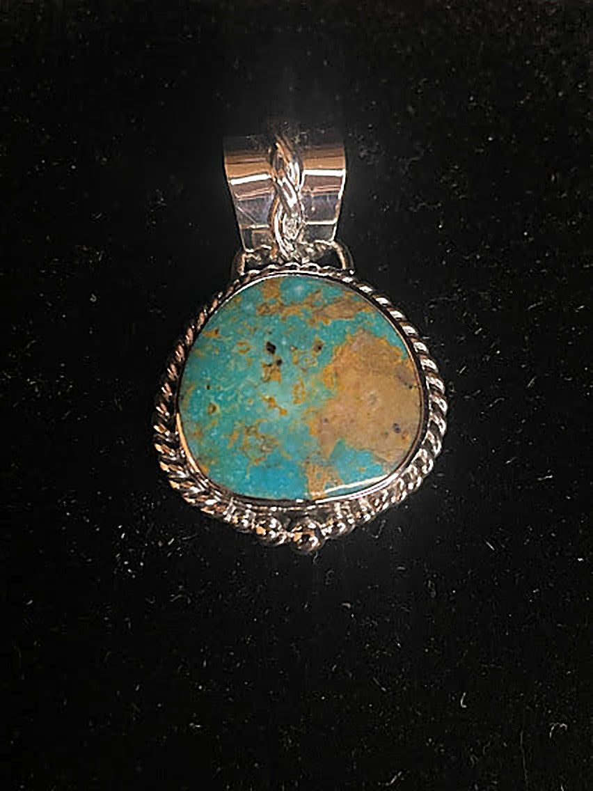 Genuine turquoise pendant - front view of the blue-green oval stone with its tan gold matrix field in its rope silver frame