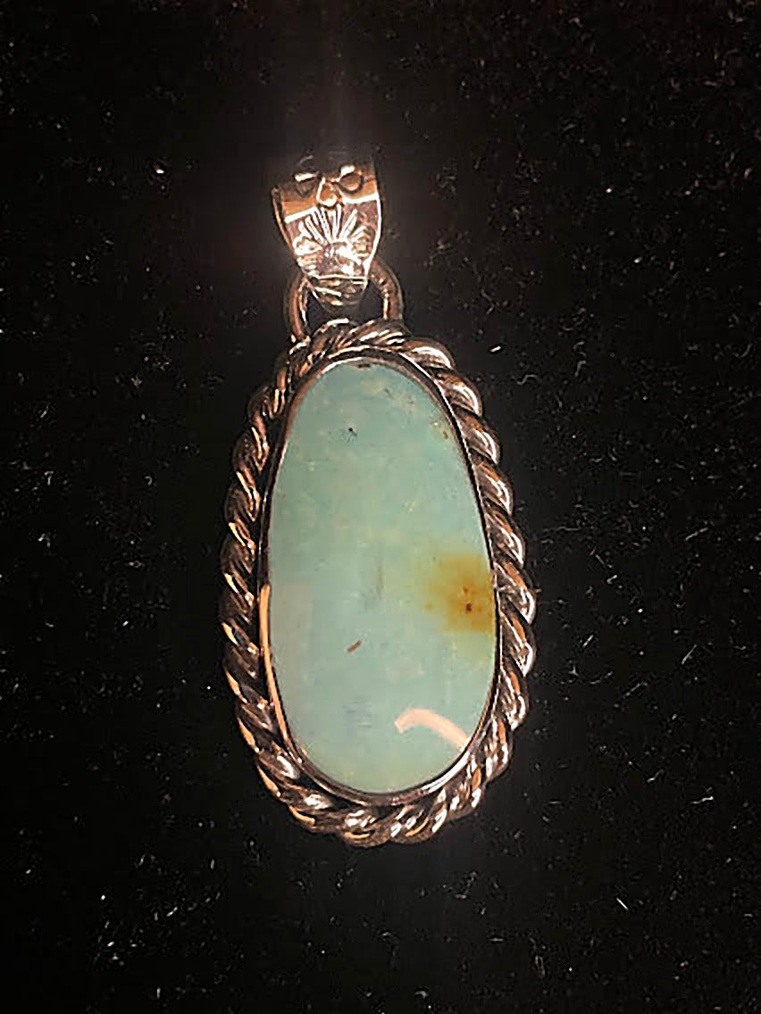 Genuine turquoise pendant - front view of the tall oval stone, pale blue-green with a gold-brown patch, in rope frame