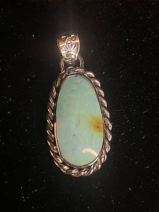 Genuine turquoise pendant - front view of the tall oval stone, pale blue-green with a gold-brown patch, in rope frame