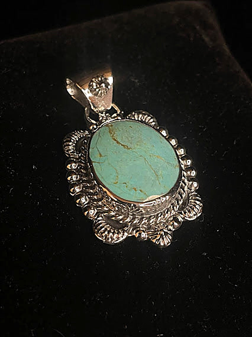 Genuine turquoise pendant - front view of the blue-green oval stone with gold matrix in its sunset sterling silver bezel