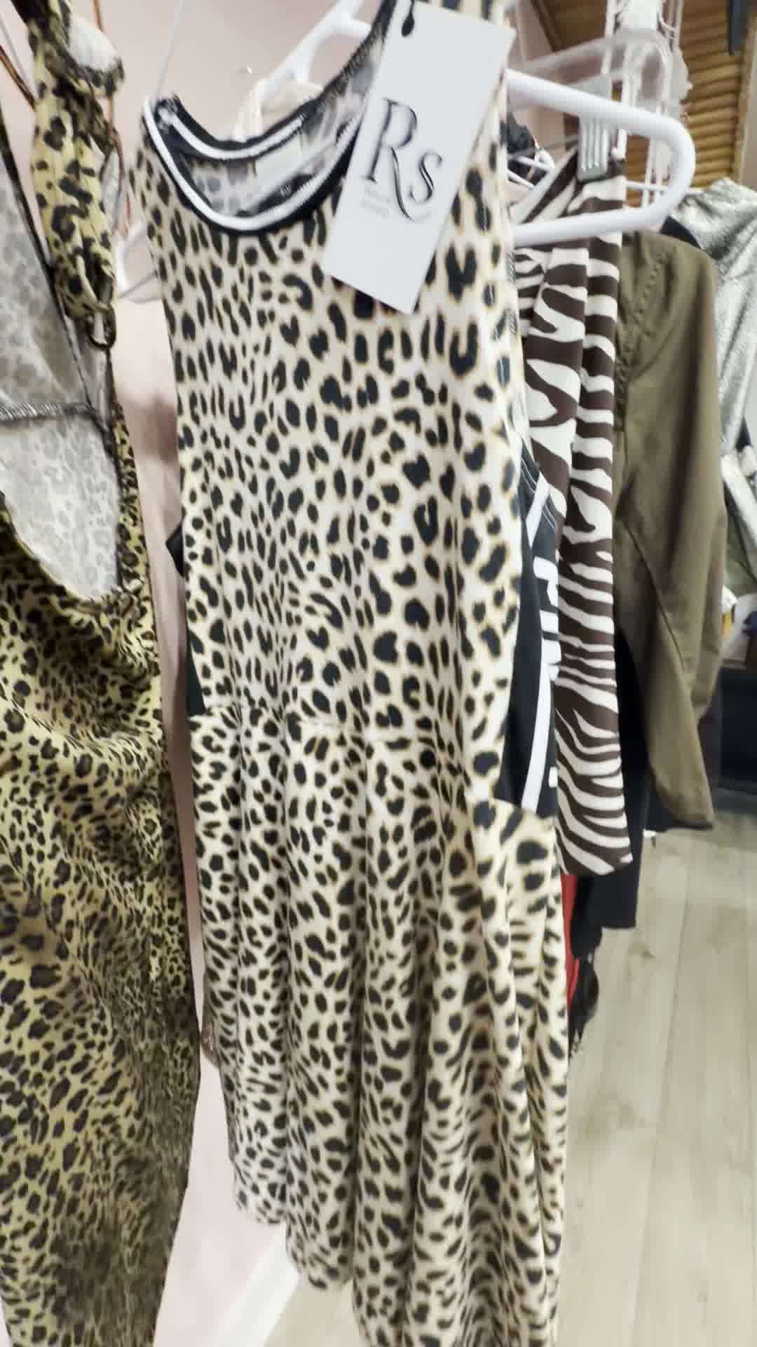 White sleeveless dress with black leopard spots and black-and-white striped trim neckline.