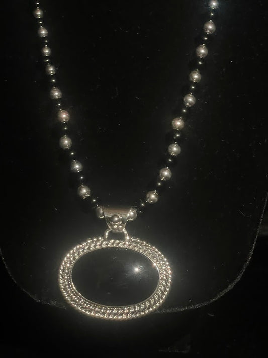 Oval obsidian pendant — full front view of the necklace on its sterling and obsidian pearl strand on black