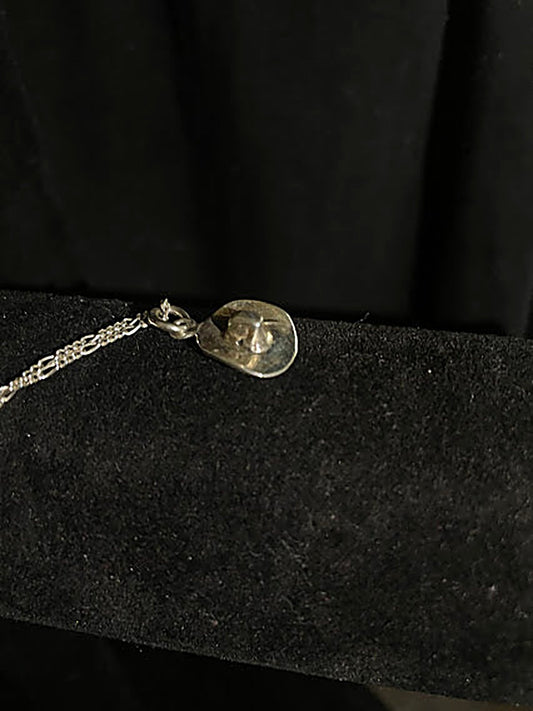 Sterling silver cowboy hat pendant — close view of the polished silver hat, its raised crown and bail, on black