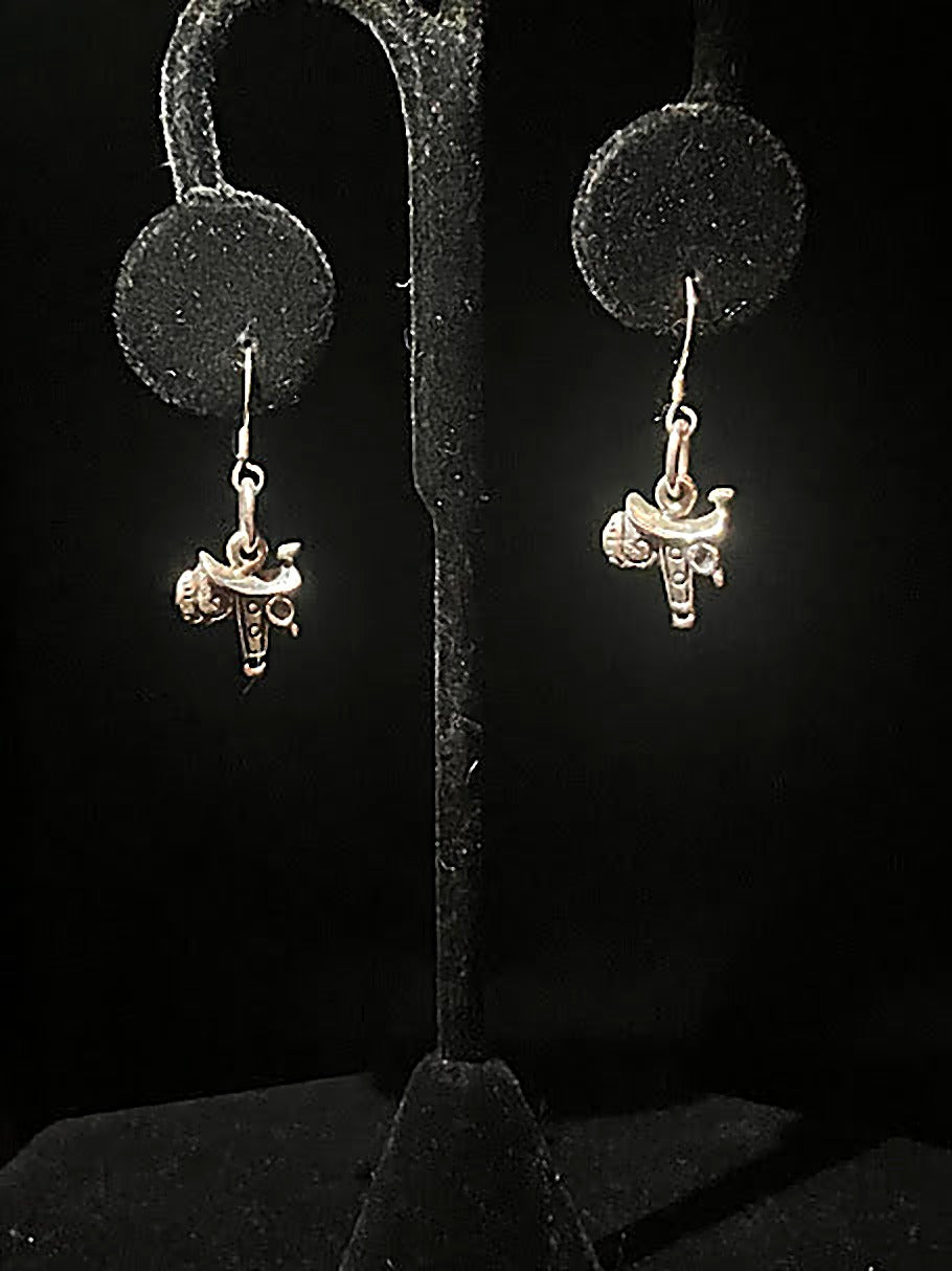Sterling silver saddle charm earrings - pair of tiny polished saddle charms on hooks, hanging on a black stand