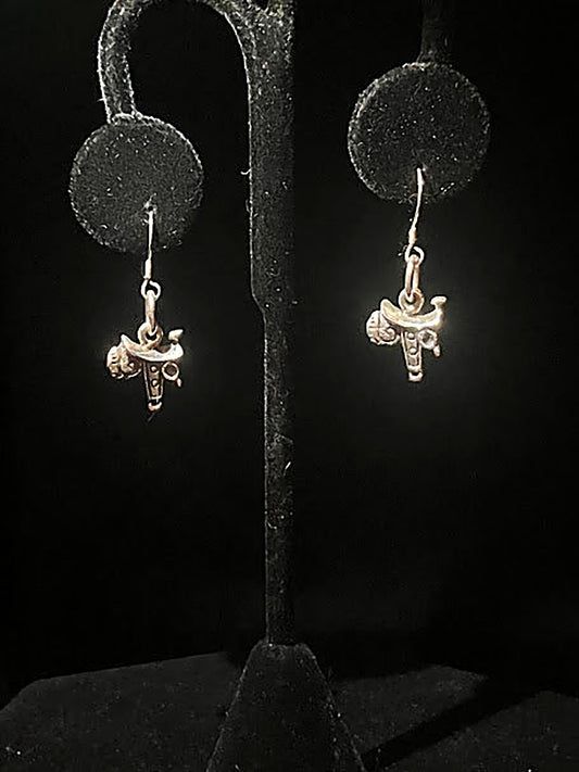 Sterling silver saddle charm earrings - pair of tiny polished saddle charms on hooks, hanging on a black stand
