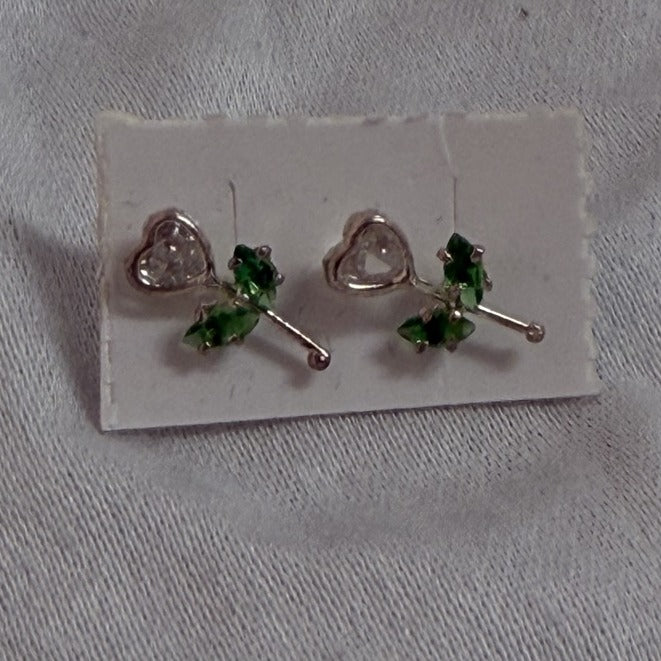 Heart stud earrings with green cubic zirconia accents on black background
