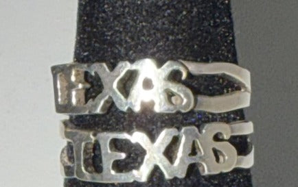 Sterling silver Texas script rings, small and large cuts, on the black display stand at Regul Silver