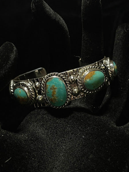 Turquoise cuff — oval turquoise stones with golden-brown matrix in rope-surround bezels, angled detail on black