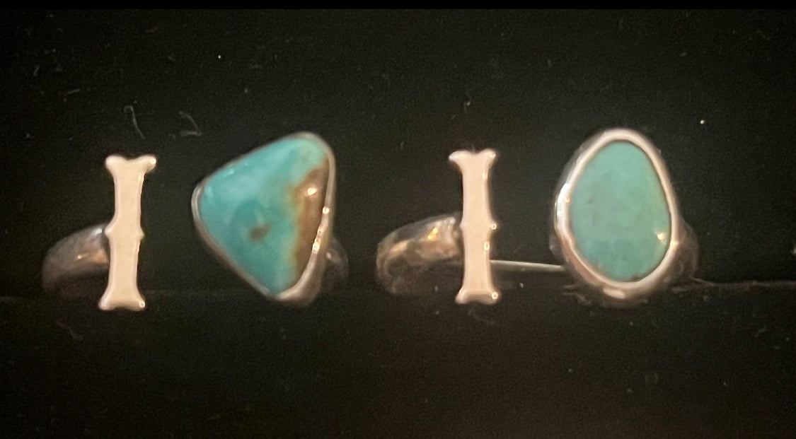 Turquoise initial ring — two letter I rings side by side, triangular and oval blue stones, on black