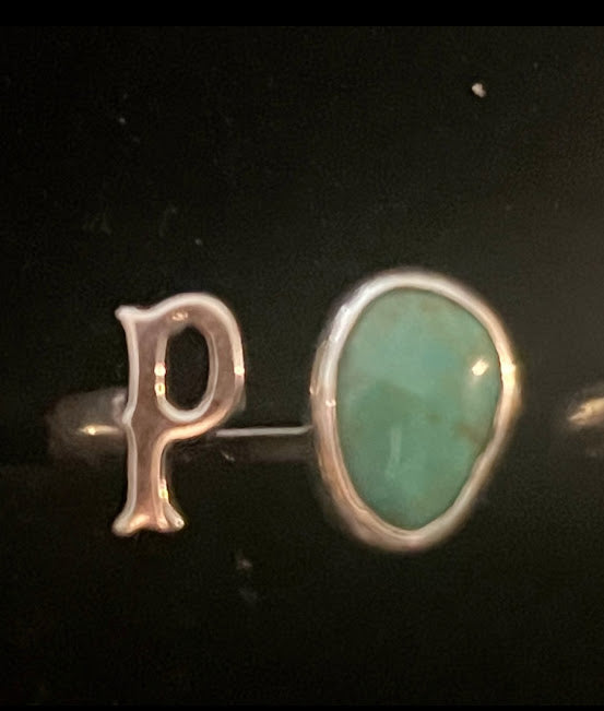Turquoise initial ring — letter P in sterling silver beside a large green teardrop stone, close view on black