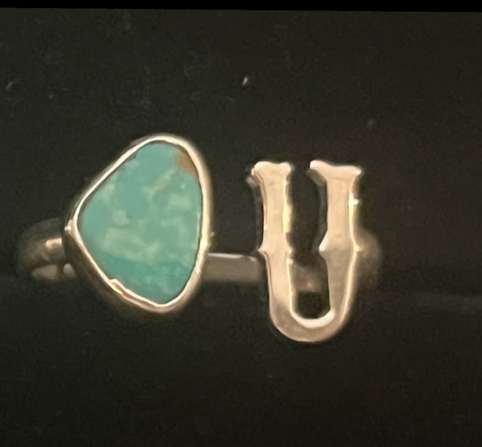 Turquoise initial ring — letter U in sterling silver beside a green teardrop stone, close view on black