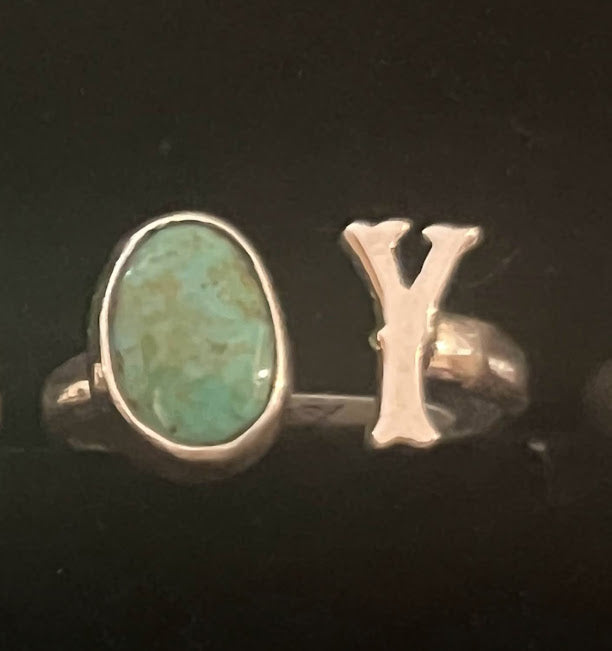 Turquoise initial ring — letter Y in sterling silver beside an oval green-blue stone, close view on black