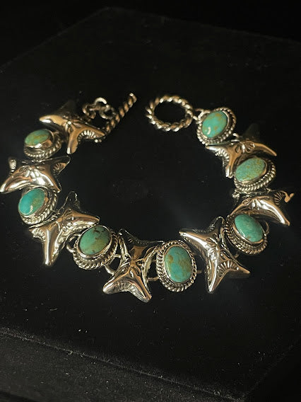 Turquoise jewelry set — its bracelet laid flat, six turquoise stones in rope bezels alternating with stamped cross-links