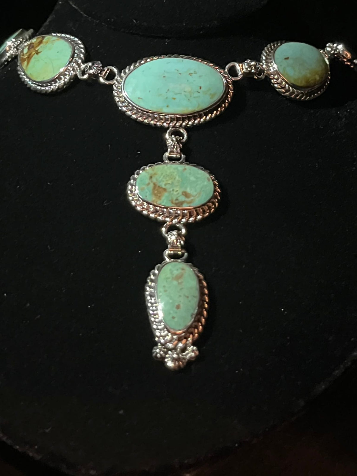 Turquoise lariat necklace — oval blue-green turquoise stones in sterling silver rope bezels on a black bust