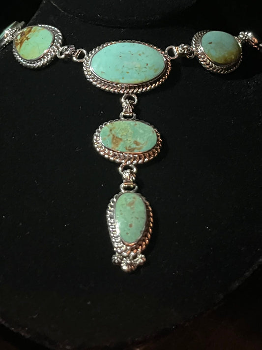 Turquoise lariat necklace — oval blue-green turquoise stones in sterling silver rope bezels on a black bust