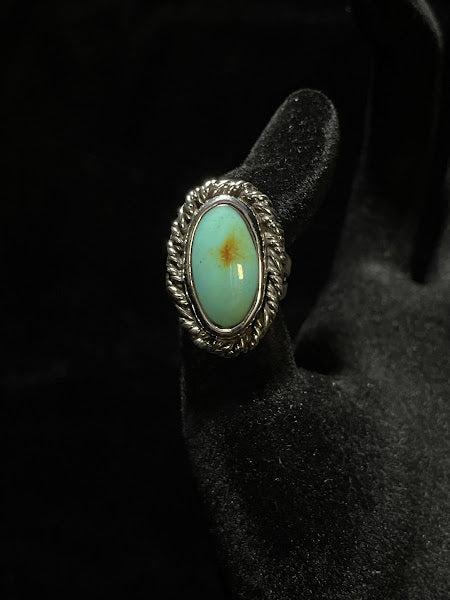 Turquoise ring — front view of the pale mint oval stone with an amber spot at its center, rope bezel, black velvet