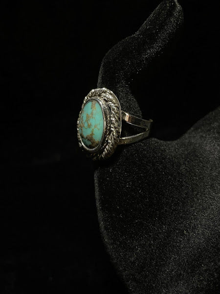 Turquoise ring — side view on black velvet, the oval stone with brown matrix seen past the rope bezel rim