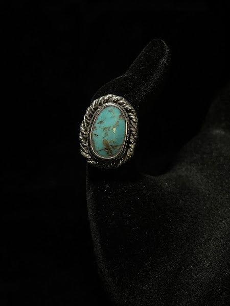 Turquoise ring — front view of the blue-green oval stone with warm brown matrix patches, sterling silver rope bezel