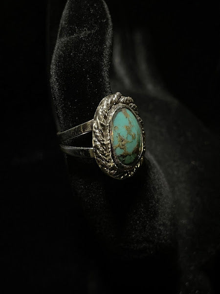 Turquoise ring — close angled view, thick rope bezel wrapping an oval stone with brown matrix, on black velvet