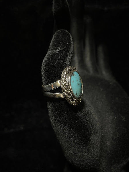 Turquoise ring — angled view on black velvet showing the split shank band rising to the rope-bezel setting